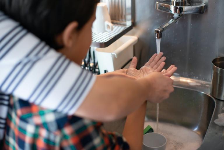 Decoratieve foto van een jongen die wordt geholpen met het wassen van zijn handen